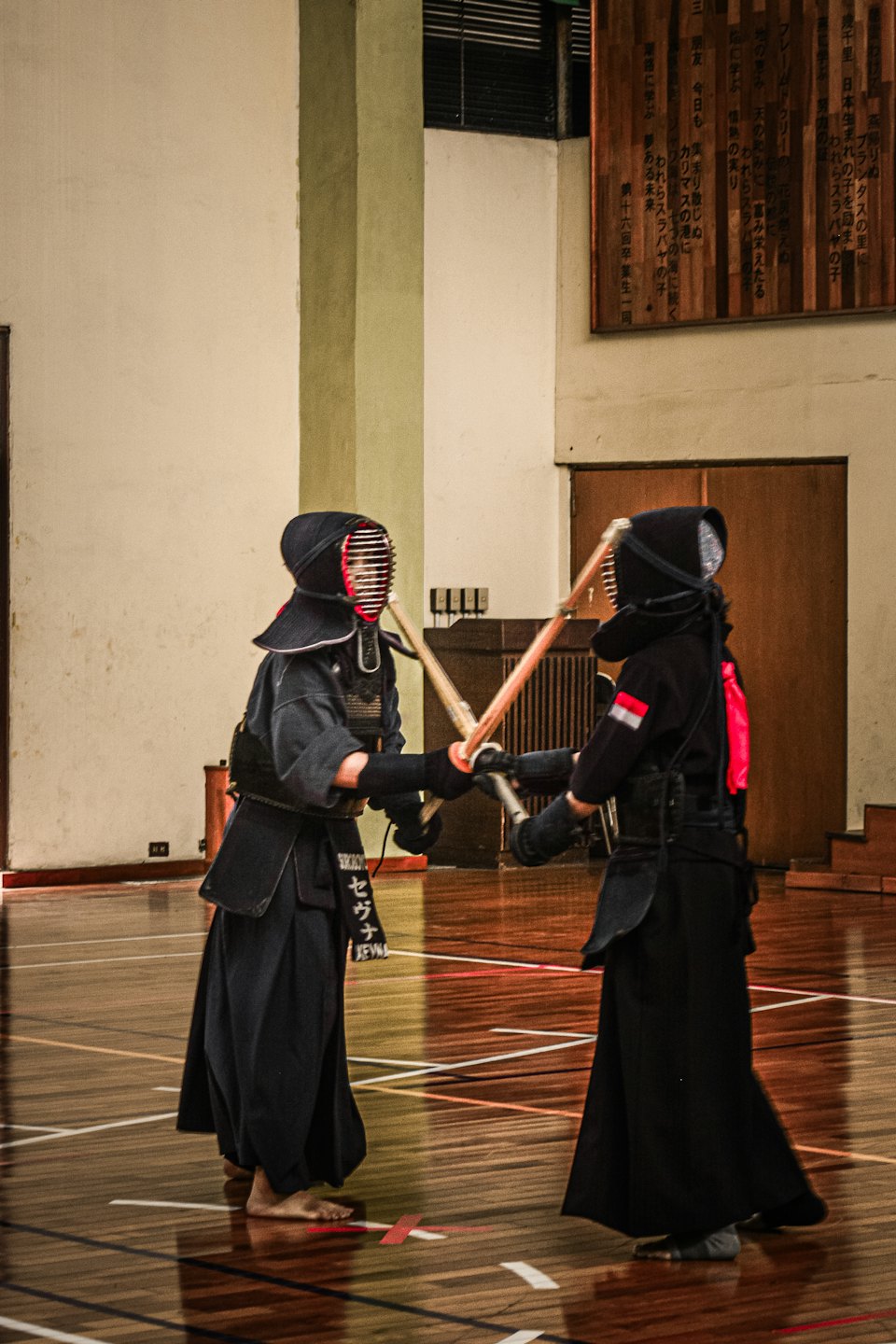 Zwei Kendo-Praktizierende, die in einem Dojo mit Bambusschwertern sparren.